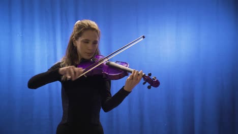 una joven músico que toca el violín en el escenario.