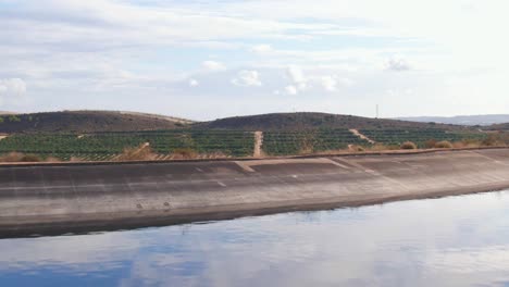 Drone-Volando-Sobre-El-Depósito-De-Agua-Para-Revelar-Campos-De-Cultivo-De-Cítricos-En-España