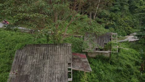 descending shot drone, aerial birds eye view of old backpacker style wooden thai bungalows that are now derelict and unused due to the effects of the pandemic on travel and tourism