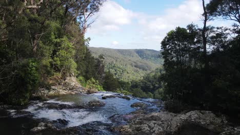 Cascadas-De-Agua-Sobre-El-Borde-De-Un-Arroyo-De-Selva-Tropical-Que-Revela-Una-Pintoresca-Cadena-Montañosa