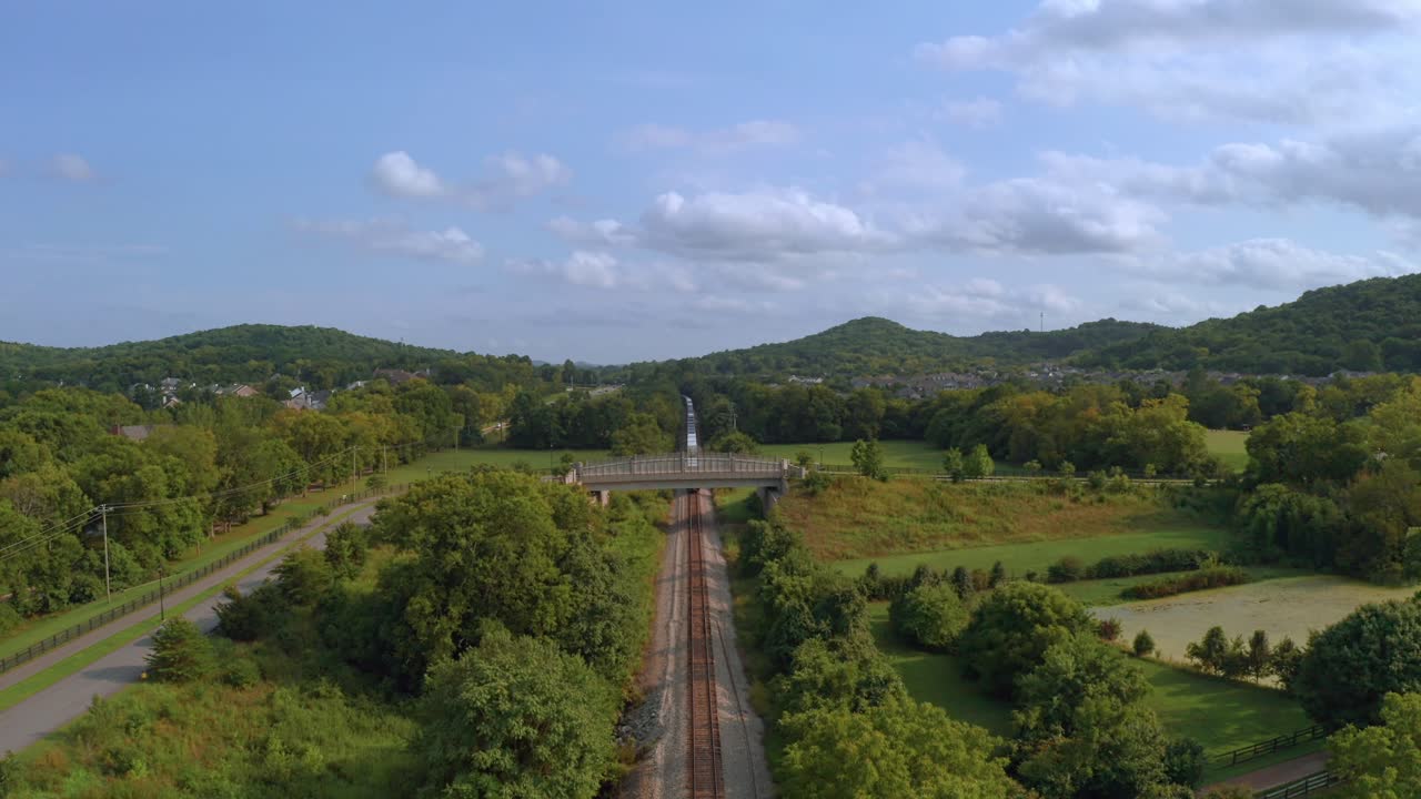 tren vagón de cola debajo de un puente que se aleja rodando mientras el dron se eleva para ver