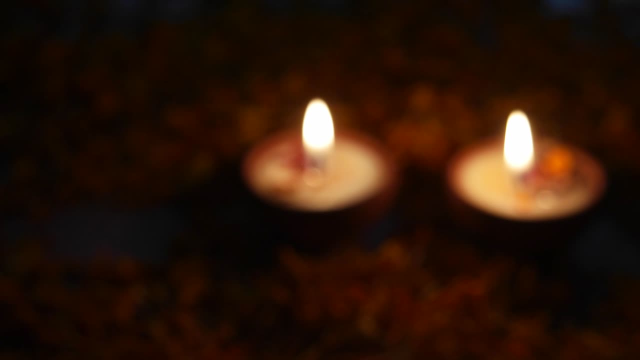 Extreme close up of a man holding a diya, focus shift and he places it with other Diyas or lamps lit up for Diwali 'Festival of light', the most important ancient Hindu festival celebrated