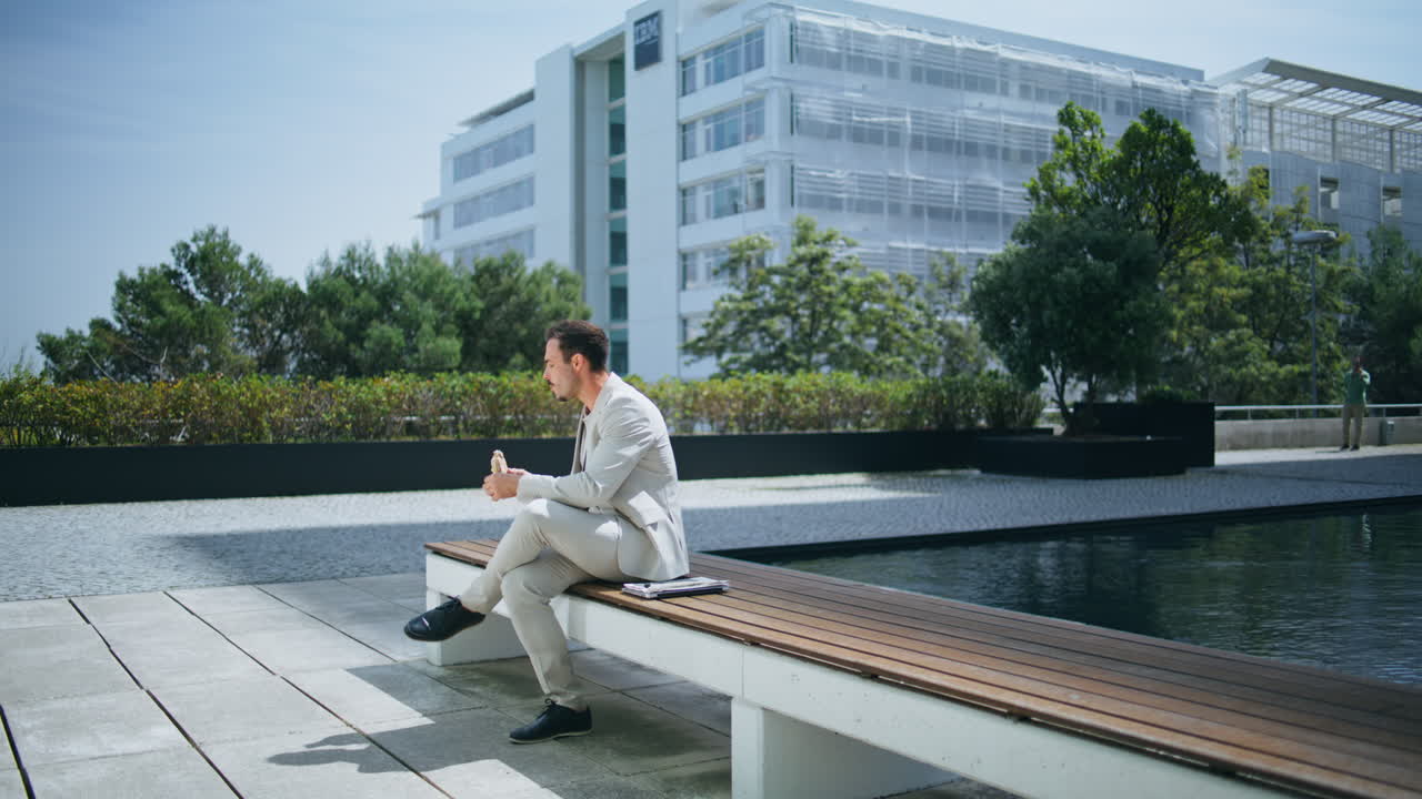 director relajado degustando el almuerzo en un banco de madera. hombre tranquilo disfrutando del descanso