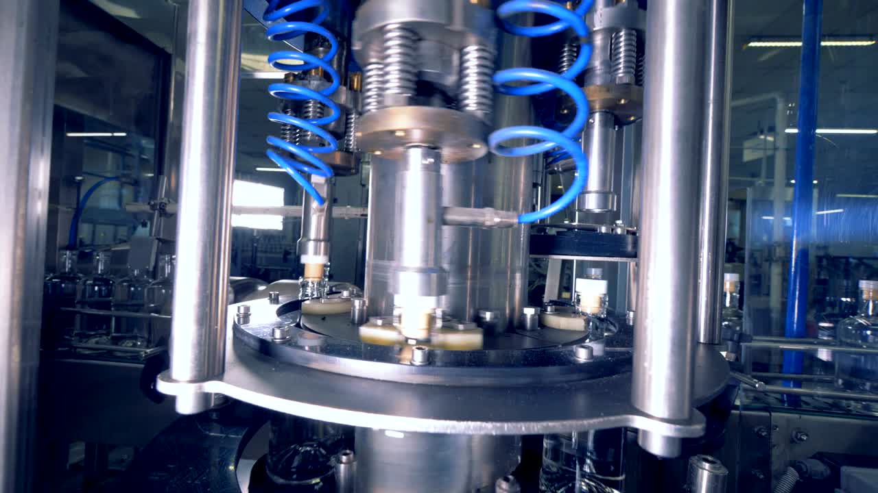 la máquina giratoria pone tapas en las botellas, de cerca.