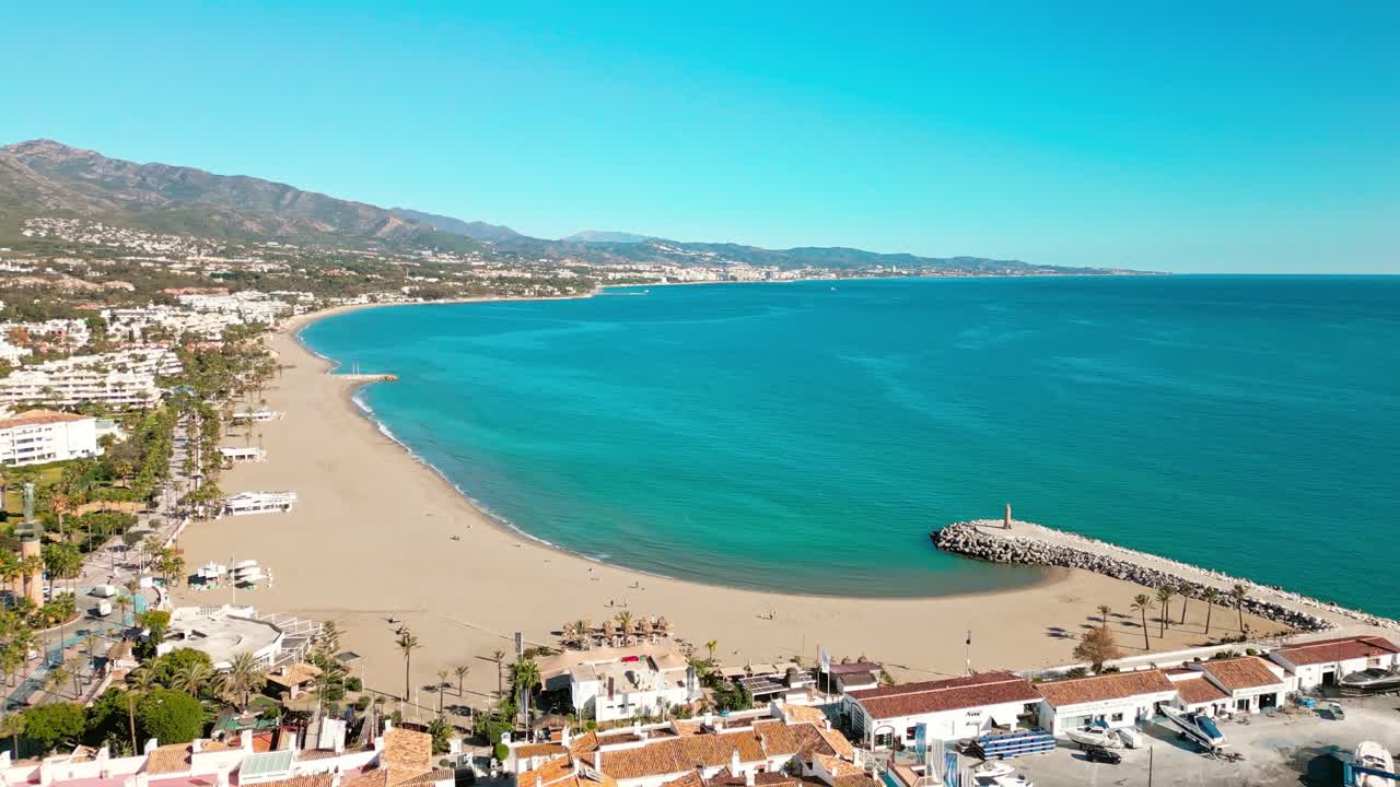 Vista aerea della costa della spiaggia e del porto turistico di Puerto Banús, Marbella, Andalusia, Costa del Sol, Spagna meridionale, con cielo soleggiato e Mar Mediterraneo