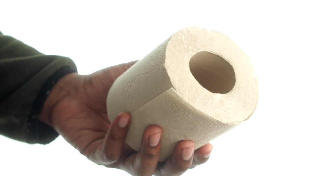 Hand holding a roll of toilet paper