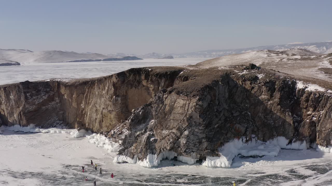 드론의 원형 비행은 얼어붙은 바이칼 호수의 바위 절벽을 둘러싸고 있습니다.