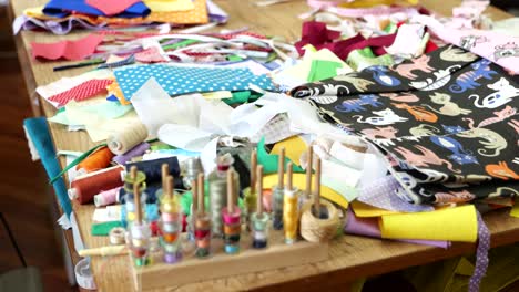 colorful spools of thread, scraps of fabric scattered on table in game factory