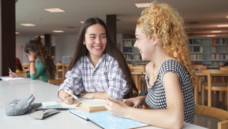 young women discussing project in library