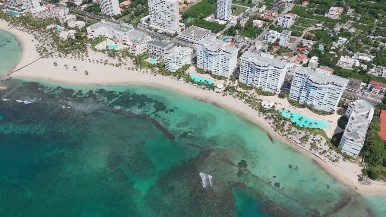 Bird's eye view of beachfront resorts and turquoise waters at Playa Juan Dolio, Dominican Republic. Crystal clear waters and white sand beach