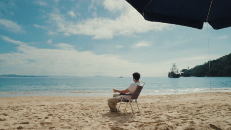 A man relaxes in a chair on a beautiful sandy beach, enjoying a sea view in Brazil, drinking a Caipirinha cocktail on his tropical summer vacation