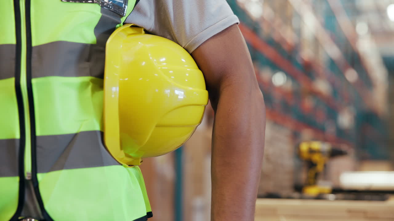 Trabajador industrial sosteniendo un casco amarillo en un almacén