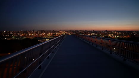 a modern bridge overlooking a lit cityscape at dusk