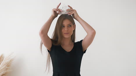 Attractive-woman-in-black-t-shirt-puts-on-stylish-crown