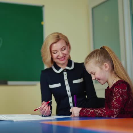 female tutor with a little girl. schoolgirl together with a beautiful teacher smiling while studying on the classroom background. education concept.