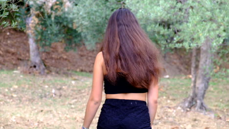 Young-brunette-girl-dancing-and-kissing-close-to-olive-trees-at-the-countryside-of-Sieci,-Pontassieve-Tuscany,-Italy