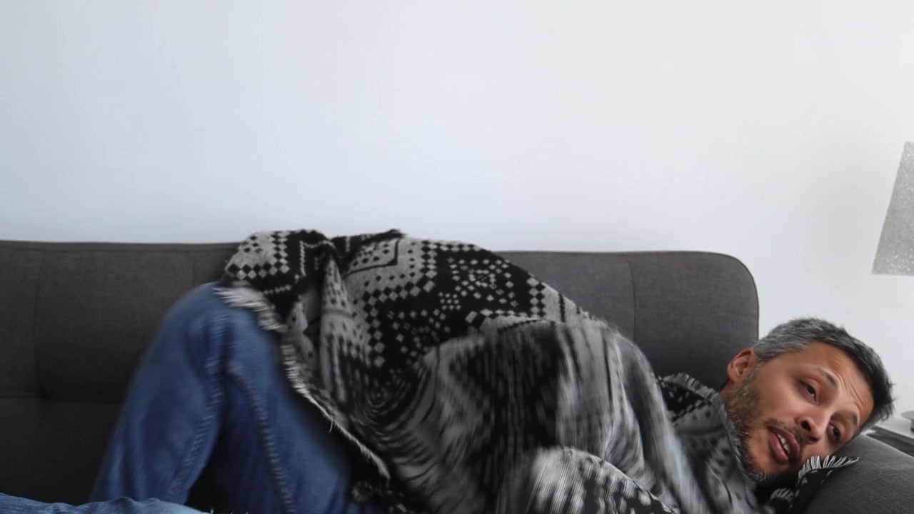 Uomo che riposa comodamente su un divano sotto una coperta