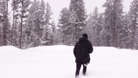 aerial view of man walking in snow while holding a remote controller