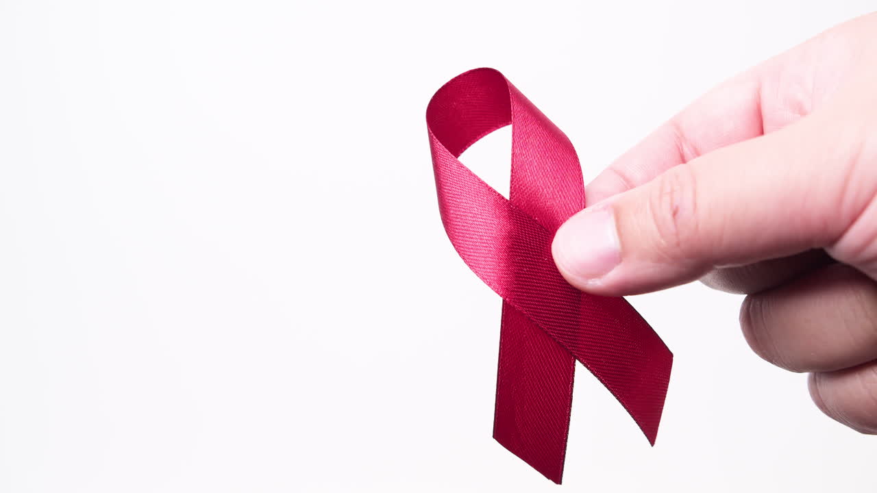 detalle de la mano masculina poniendo cinta en color rojo sobre fondo blanco