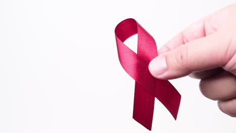 detail of male hand putting ribbon in red color on white background