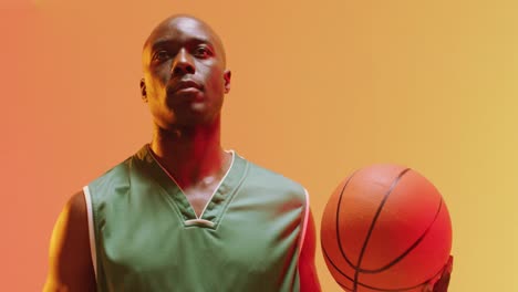 Video-of-african-american-male-basketball-player-holding-ball-on-orange-background