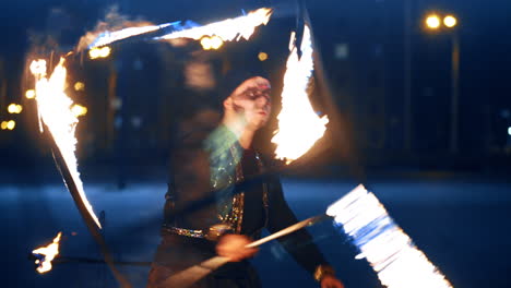 man in costume turns a big burning cube around himself. artist performs fire show to the public at night.