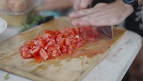 close-up of hands chopping tomatoes on a cutting board