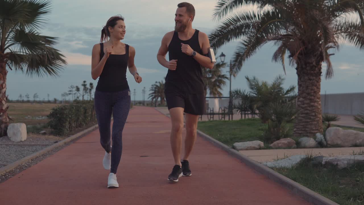 pareja corriendo por un camino costero al atardecer