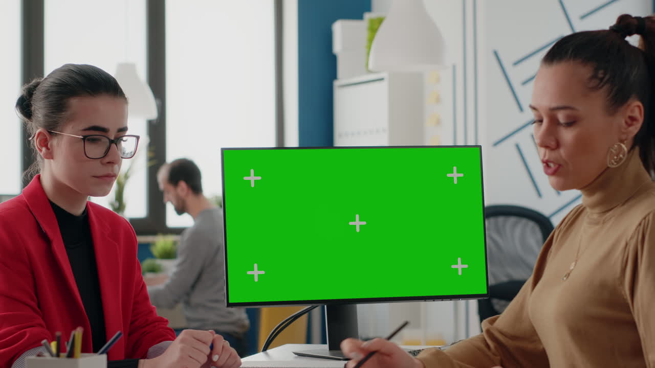 Coworkers working with green screen on monitor