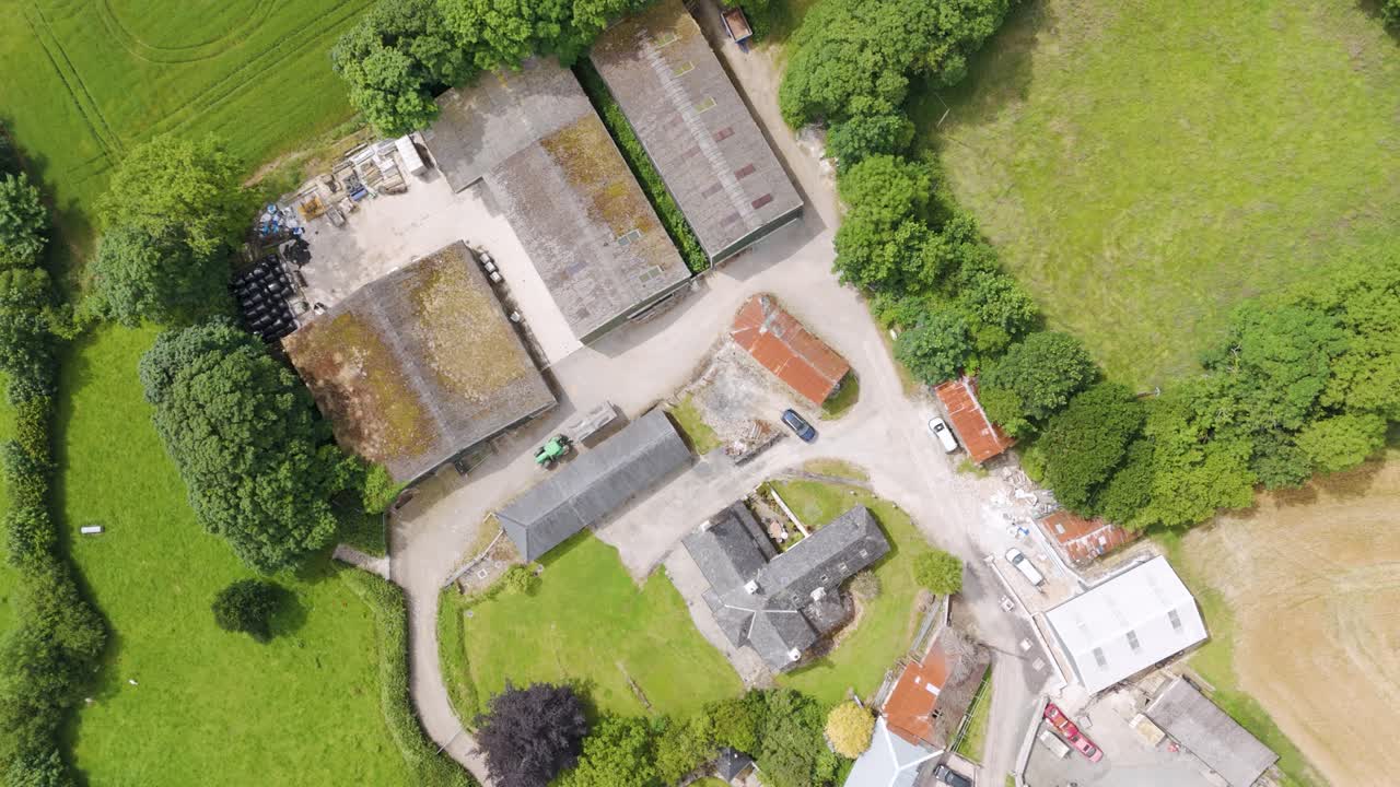 Top down aerial view of a smallholding UK farm, showing buildings, green fields, and surrounding rural landscape