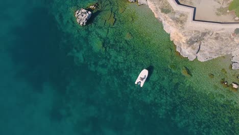 Speed-boat-parked-on-a-rocky-beach-in-the-green-and-blue-pristine-water-of-a-natural-lake