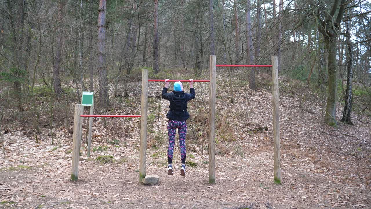 disparo estático de mujeres haciendo pull-ups en una barra en el bosque para el ejercicio