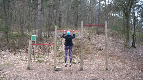 static shot of women doing pull-ups on a bar in the forest for exercise