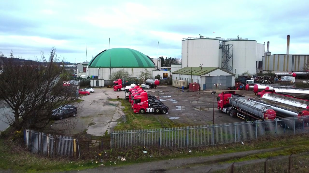 industrial green domed food waste biodegradable recycling silo facility aerial descending view to trucks