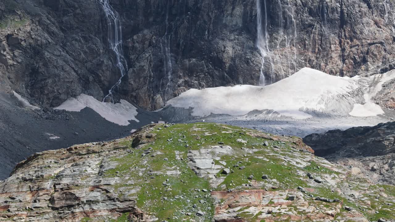 Ingrandisci il clip video aereo che mostra il ghiacciaio del Fellaria circondato da un aspro territorio alpino, cascate e formazioni rocciose scoperte