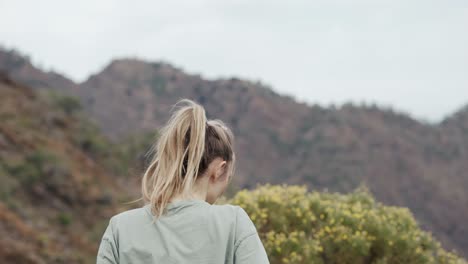 woman walks up on the cliff high, stands to enjoy the view