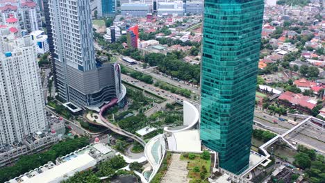 tall high-rise commercial buildings and mall near highway with vehicles in west jakarta