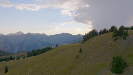 Boom-up-over-tree-lined-ridge-and-towards-mountain-range-and-sunset-in-the-Rocky-Mountains-in-Colorado-on-a-beautiful-summer-day