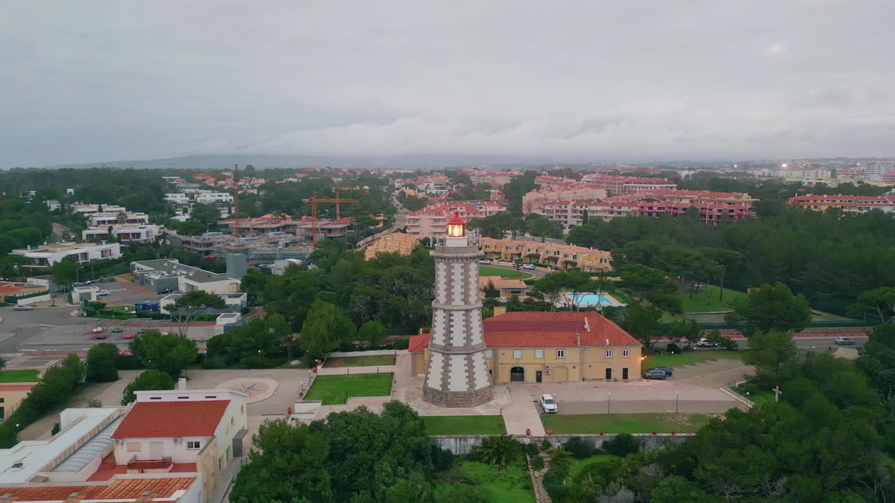 Maritime beacon lighting seaside town under cloudy sky drone. Coastal lighthouse