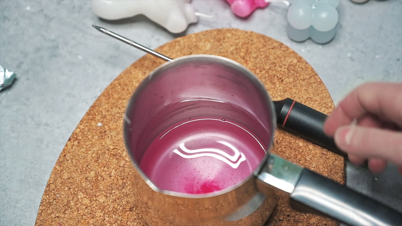 Hand made candles production, female hand checking temperature and mixing melting wax in a pot. Slow motion