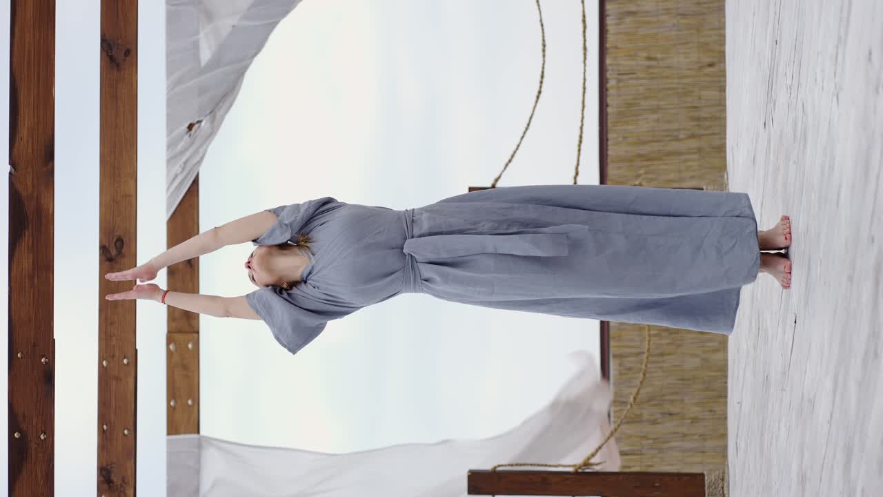 joven rubia con túnica azul haciendo yoga en la terraza