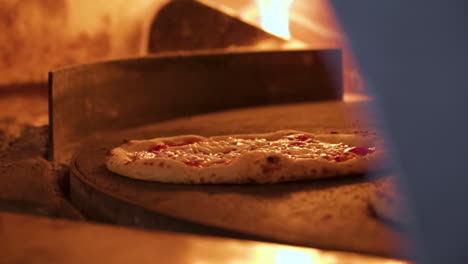 handcrafted artisanal pizza bakes and bubbles near flames in traditional wood burning pizza oven, slow motion close up 4k