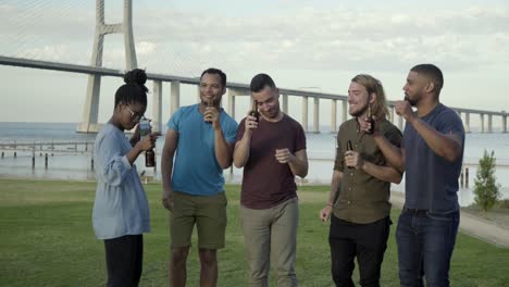 Cheerful-young-people-holding-beer-bottles-and-dancing