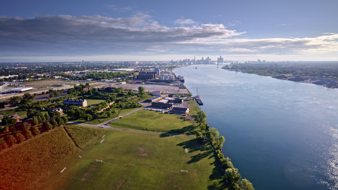 Smooth drone shot soaring above the Detroit River with Detroit’s skyline and a passing freighter in view