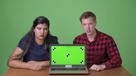 joven pareja de negocios multiétnica juntos contra un fondo verde