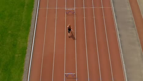 Female-athletic-jumping-over-hurdle-on-sports-track-4k