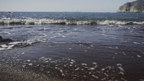 Zeitlupenaufnahme-Von-Wellen,-Die-An-Hellen-Tagen-Auf-Den-Schwarzen-Sandstrand-Rollen