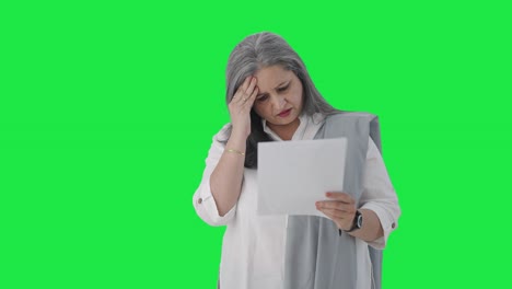 mujer gerente india de alto rango estresada leyendo informes de negocios pantalla verde