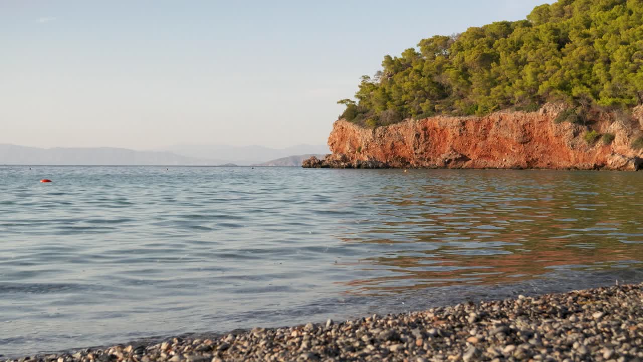 Paesaggio tranquillo in una piccola baia oceanica con scogliere in lontananza.