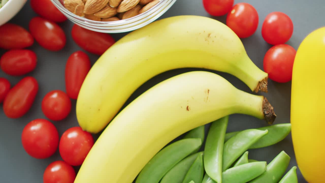 video de frutas y verduras frescas y cuencos de nueces y semillas sobre fondo gris